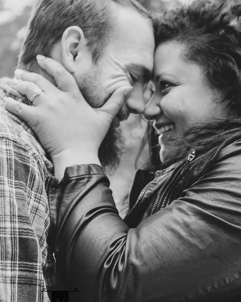 Black and white close-up of couple leaning foreheads together, laughing