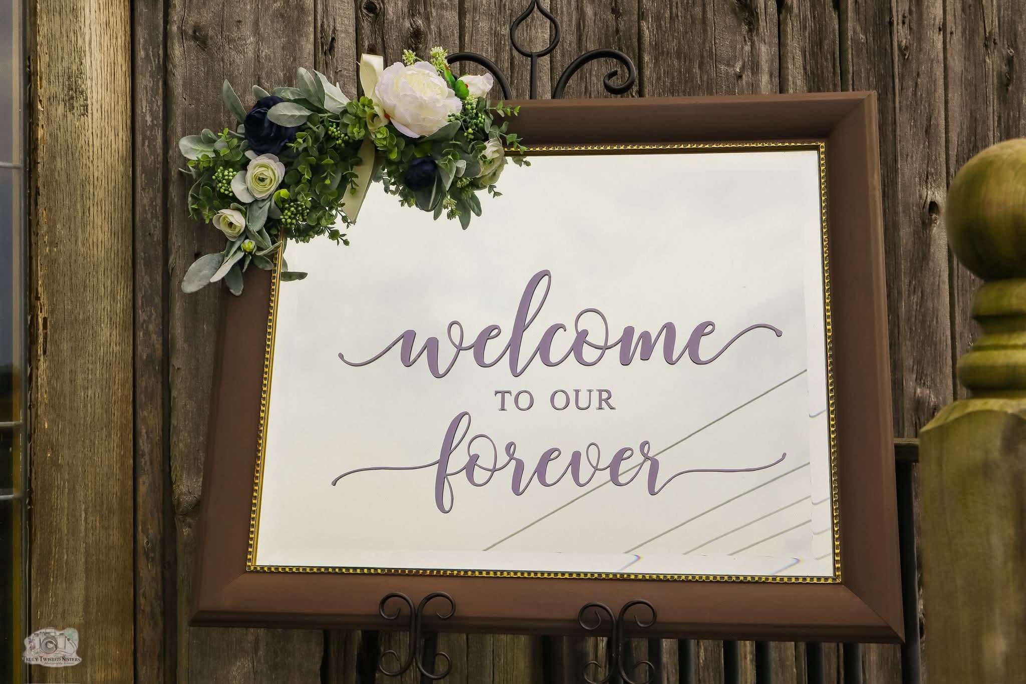 Elegant floral welcome sign reading 'Welcome to our forever' on a rustic wood backdrop